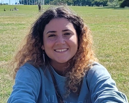 Coral smiling and sitting on green grass.